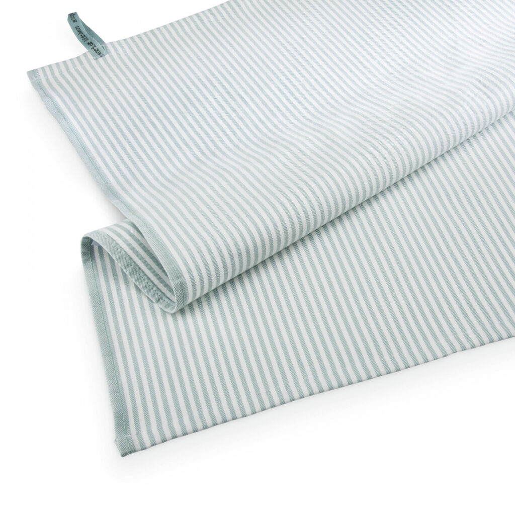 De Walra-theedoek Superior Dry Cloth Jade heeft lichtblauwe en witte strepen, is netjes opgevouwen en is in de hoek voorzien van een klein stoffen label.