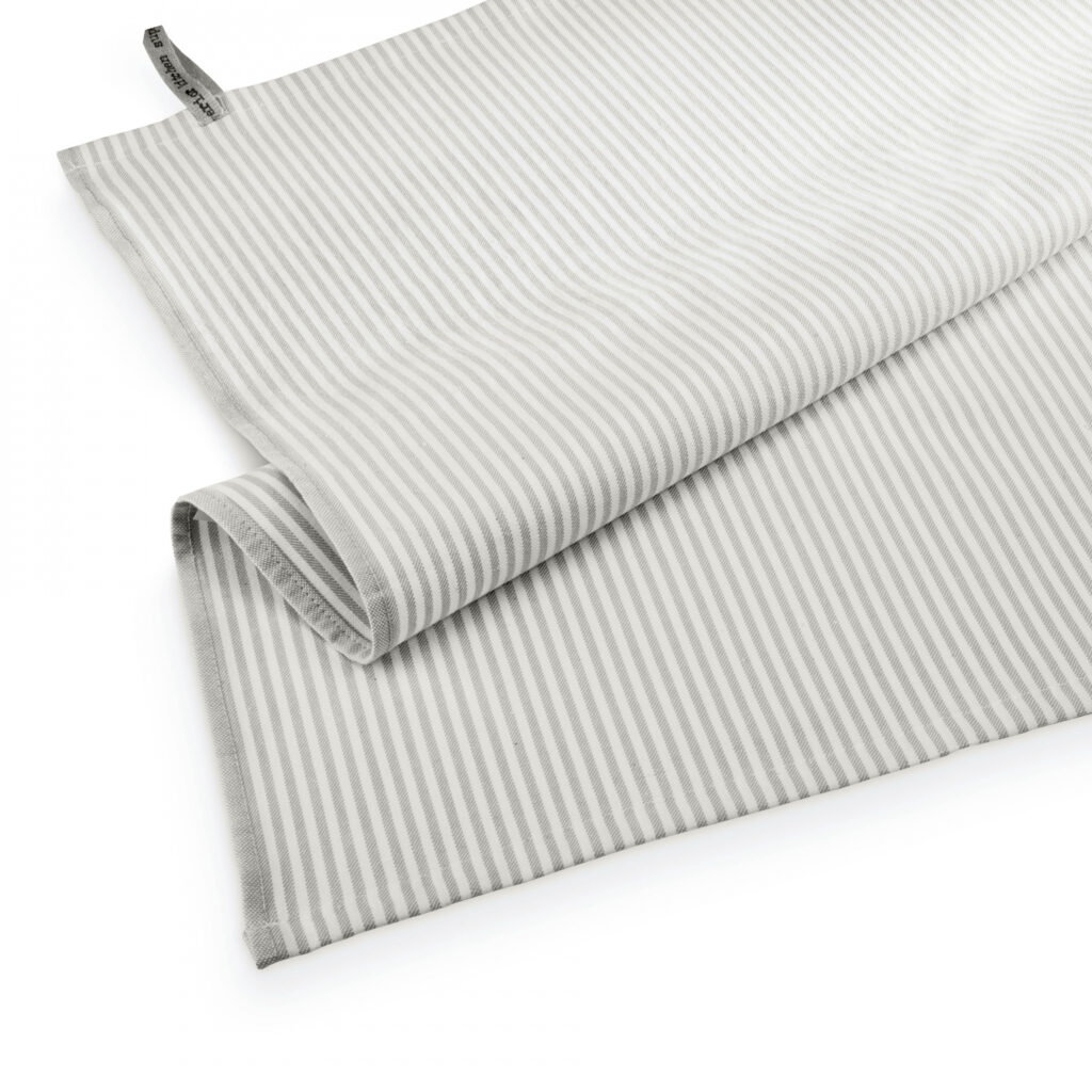 De Walra Theedoek Superior Dry Cloth Taupe is een gevouwen theedoek met lichtgrijze en witte strepen en een klein stoffen label in de hoek.