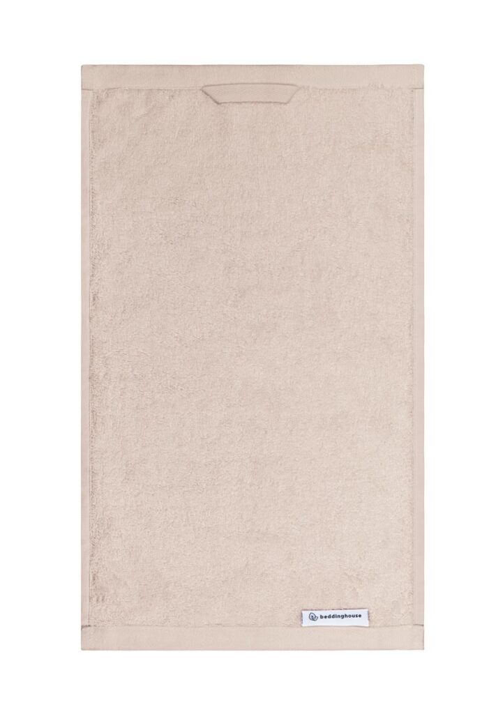 Deze beige rechthoekige handdoek uit de Beddinghouse Care Gastendoek Beige-set heeft een gestikte rand en een wit Beddinghouse-label in de hoek.