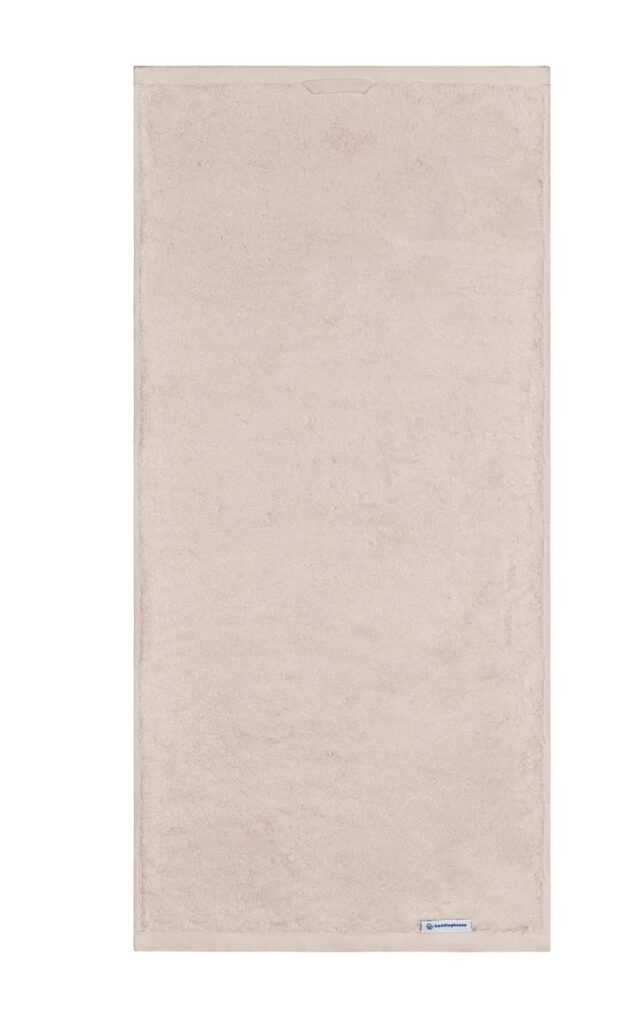 De Beddinghouse Care-handdoek in beige ziet er heerlijk zacht en volumineus uit, met een subtiel stoffen label aan de rand.