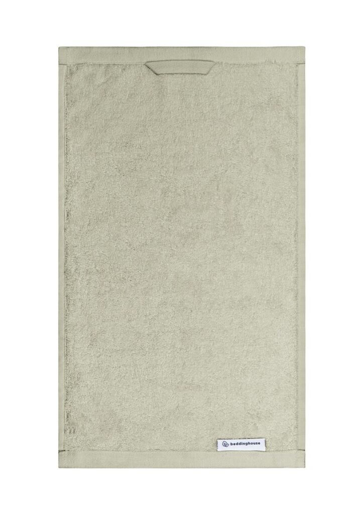Dit groene, rechthoekige gastendoekje uit de Beddinghouse Care Gastendoek Groen-set is voorzien van een klein Beddinghouse-merklabel aan de rand.
