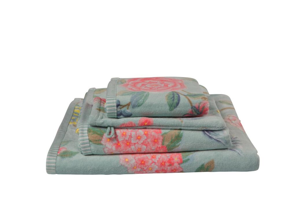 De Pip Studio Good Evening-washandjes in blauw bestaan uit drie washandjes met een zachte groene achtergrond en roze en koraalkleurige bloemen met groene blaadjes.
