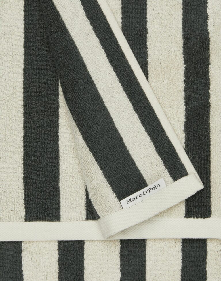 Deze close-up toont de Marc O'Polo Heritage-handdoek in antraciet met verticale zwarte en witte strepen en een subtiel merklabel.