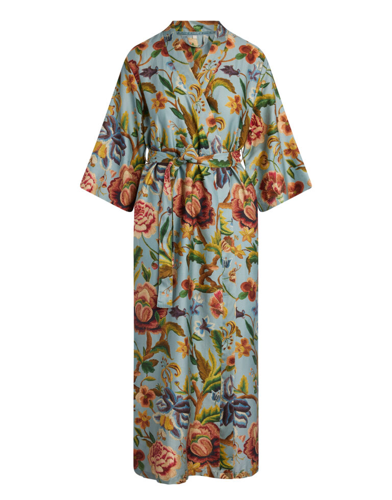 De Essenza Juliet Roselina Kimono in Surf Green is een lange kimono met ceintuur en wijde mouwen, versierd met kleurrijke bloemen op een lichtblauwe achtergrond.