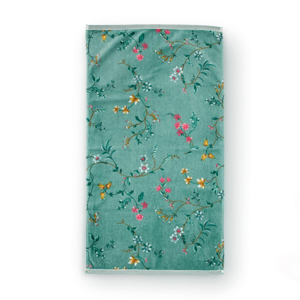 De opgevouwen blauwgroene Pip Studio Les Fleurs-handdoek heeft een bloemenpatroon met takjes en roze, gele en witte bloemen.