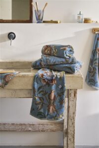 Op een rustieke wastafel ligt een stapel Pip Studio Secret Garden Washand Blauw-set van drie, met een bijpassende handdoek ernaast.