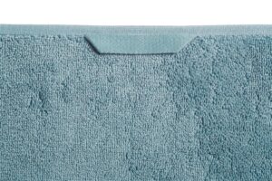 Close-up van het Beddinghouse Sheer gastendoek in blauw met een lichtblauwe structuur en een rechthoekig label aan de bovenrand.