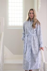 Een vrouw met lang blond haar draagt de Pip Studio Tile de Pip-badjas in blauw met gestreepte accenten en geniet van de zon.