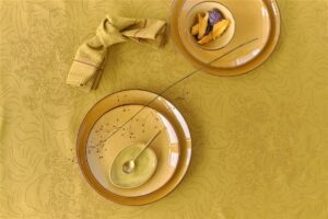 Het gele Van Gogh Tournesol-tafelkleed vormt een bloemrijke achtergrond voor bloemig servies, bestek, fruit en een sierlijk takje.
