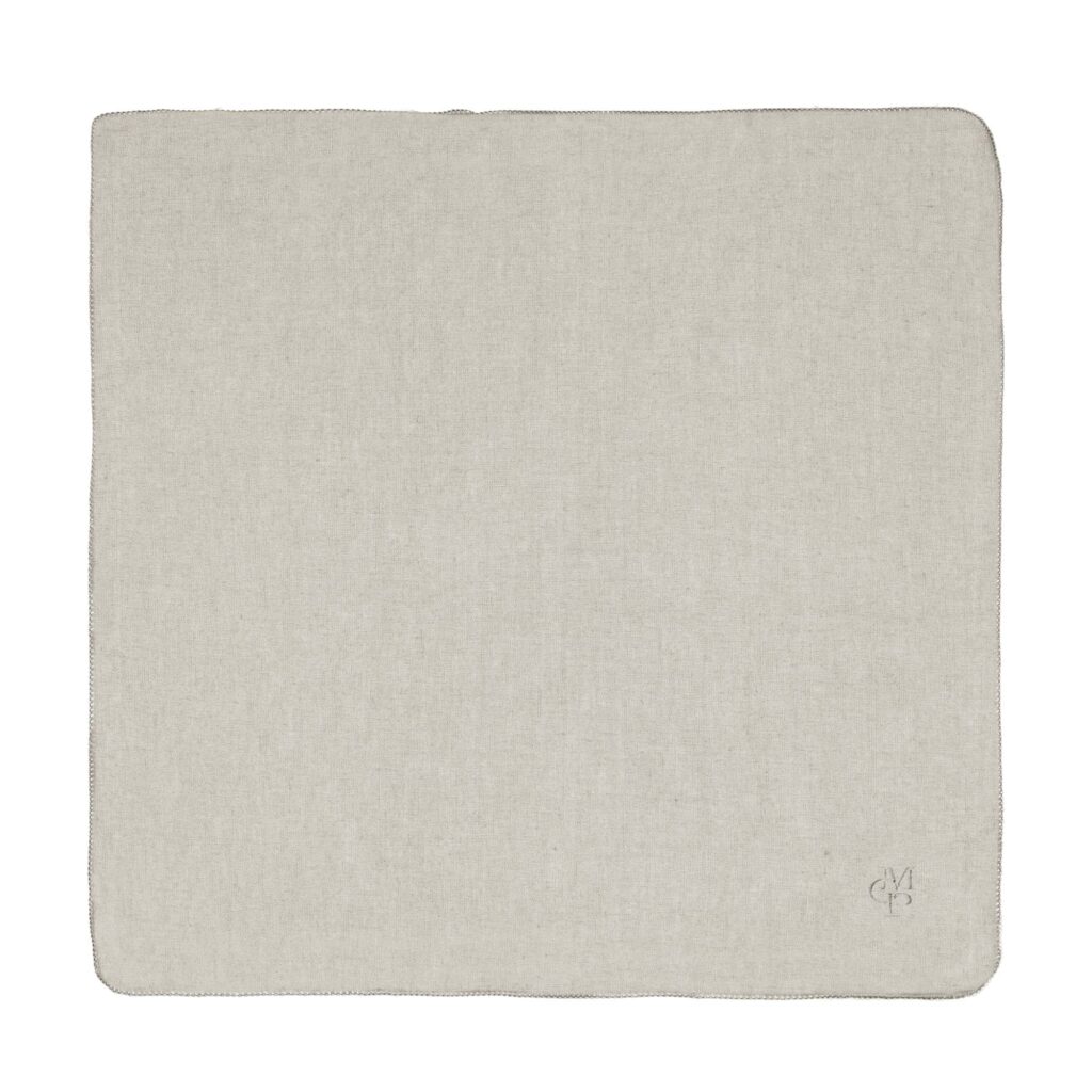Het Marc O'Polo Valka-servet in de kleur Oatmeal is een lichtbeige linnen servet met nette randen en een subtiel monogram in de hoek.