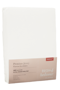 Een verpakt wit hoeslaken van Beddelicious Premium Jersey Hoeslaken Ivory, voorzien van productinformatie en het Beds & Bedwear Collection-logo op een beige etiket aan de onderkant.