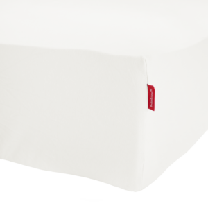 Een close-up van het Beddelicious Premium Jersey-hoeslaken in de kleur Ivory op een matras, met een rood stoffen label in de hoek.