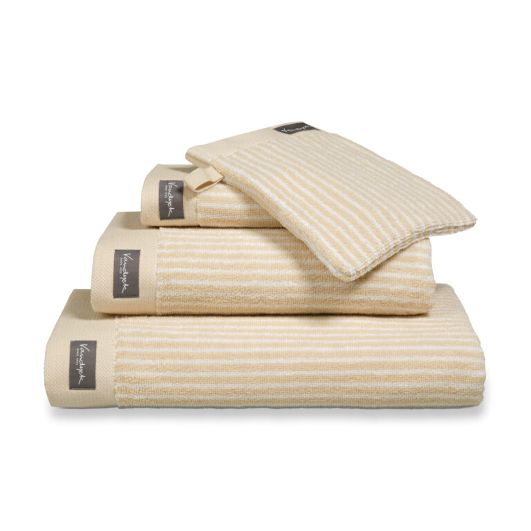 Het De Vandyck Home Petit Ligne-badlaken in gebleekt zand heeft beige en witte strepen en een donker label met witte tekst.