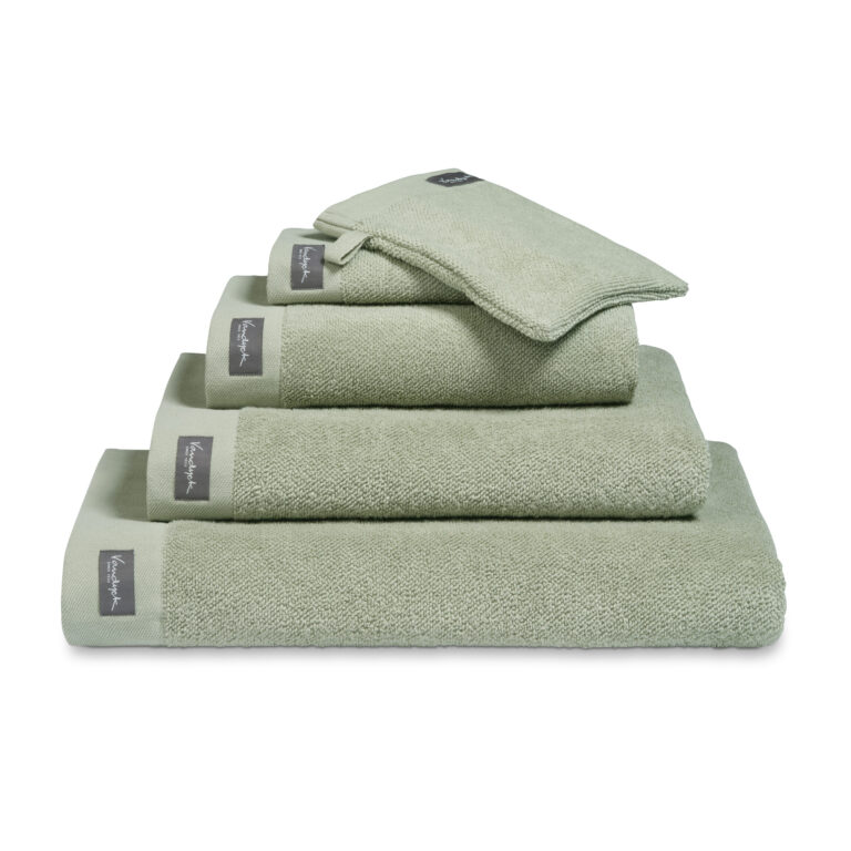 Een set Smoke Green Vandyck Home Uni-badlakens ligt netjes opgestapeld, met daarbovenop een bijpassend etui met een grijs label.