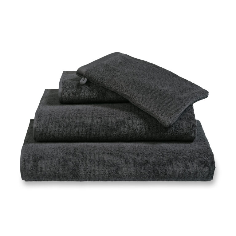 Een keurig gestapelde Vandyck Verona Plain badlaken-set in Off Black, bestaande uit een groot badlaken, een washandje en een handdoek.