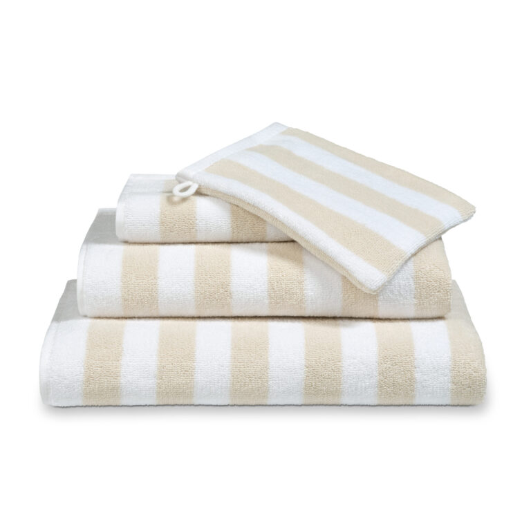 De Vandyck Verona Stripes Badlaken Desert is een beige handdoek met witte strepen, stijlvol gestapeld met bijpassend textiel.