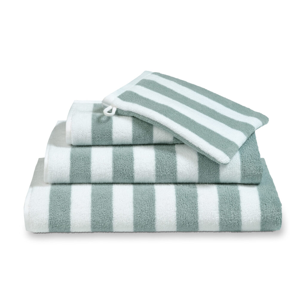 Het Pearl Blue Vandyck Verona Stripes-badlaken is netjes opgevouwen, samen met een bijpassend gestreept washandje.