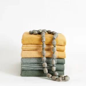 Vier Vandyck Home Petit Ligne Handdoek Olive: handdoeken in mosterdgeel, lichtgrijs en groen met grijze kralen erop.