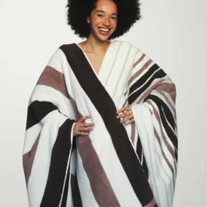 Een glimlachende persoon met een afro houdt de Vandyck Ontario-handdoek in de kleur Mauve vast.
