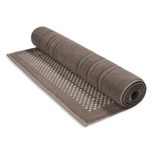 De Vandyck Houston-badmat in de kleur Espresso ligt gedeeltelijk uitgerold en heeft een gestructureerde, antislip onderkant met een stippenpatroon.