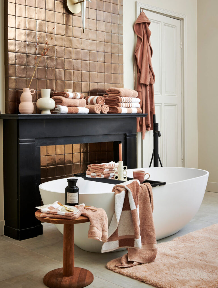 In deze moderne badkamer zorgen zachte bruine tinten en de beste handdoeken van 2026 voor comfort bij het vrijstaande bad en sfeervolle details.