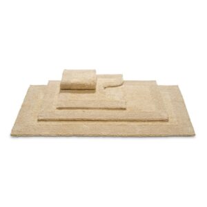 De Vandyck Scala Luxury-badmat Beach in beige ligt opgestapeld met andere badmatten, van groot onderaan tot klein bovenaan.