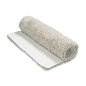 De Vandyck Toronto badmat Stone is een beige, zachte badmat met een donzige textuur, die gedeeltelijk is opgerold en comfortabel in gebruik is.