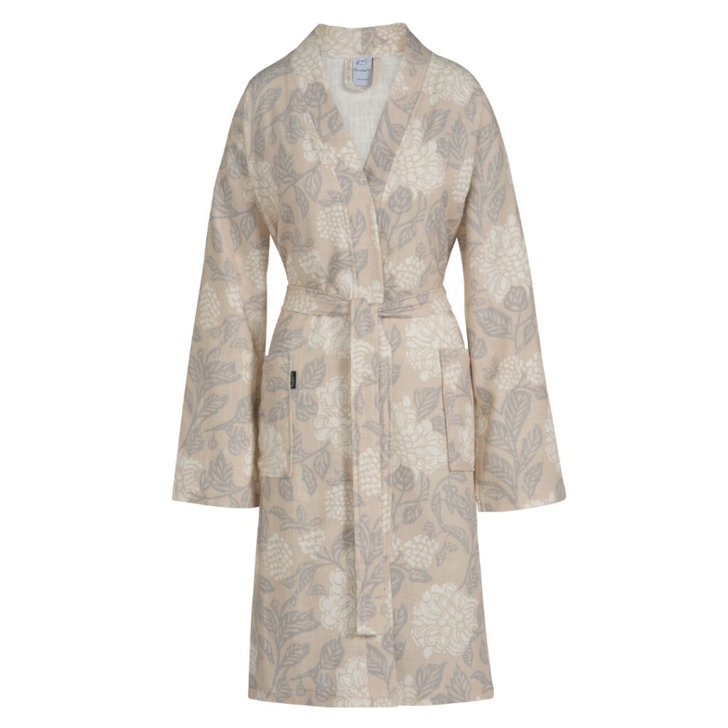 De Vandyck Marly Linen L is een beige badjas met bloemenprint, lange mouwen, twee steekzakken en een bijpassende ceintuur.