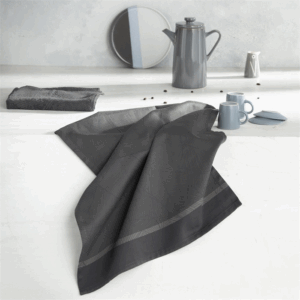 De DDDDD-keukendoek in de kleur Barrier Grey is netjes opgevouwen, omringd door grijze mokken, borden, een theepot en een extra doek.