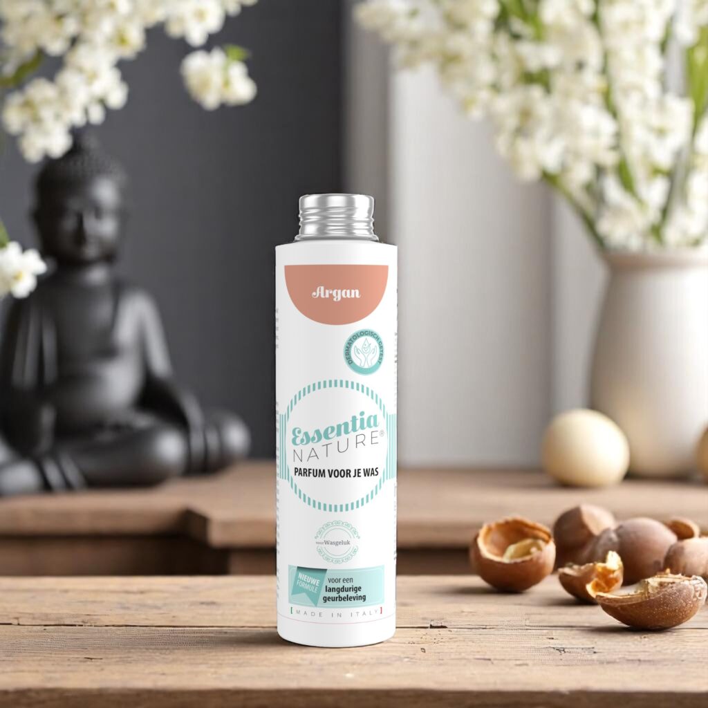 Essentia Wasparfum Argan 250 ml staat op een houten tafel tussen argannoten en witte bloemen, met een vage afbeelding van Boeddha op de achtergrond.