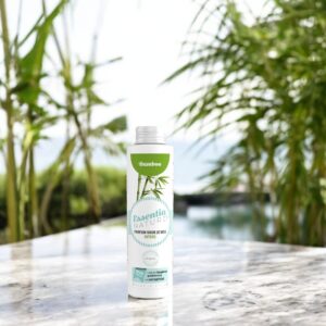 Essentia Wasparfum Bamboo 250 ml staat buiten op een marmeren oppervlak tussen groene bamboestruiken bij een kabbelend waterornament.