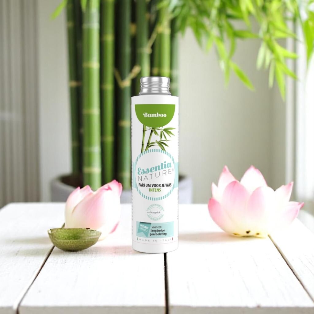 Essentia Wasparfum Bamboo staat naast twee roze lotusbloemen en een schaaltje, omringd door groene bamboestengels en bladeren.