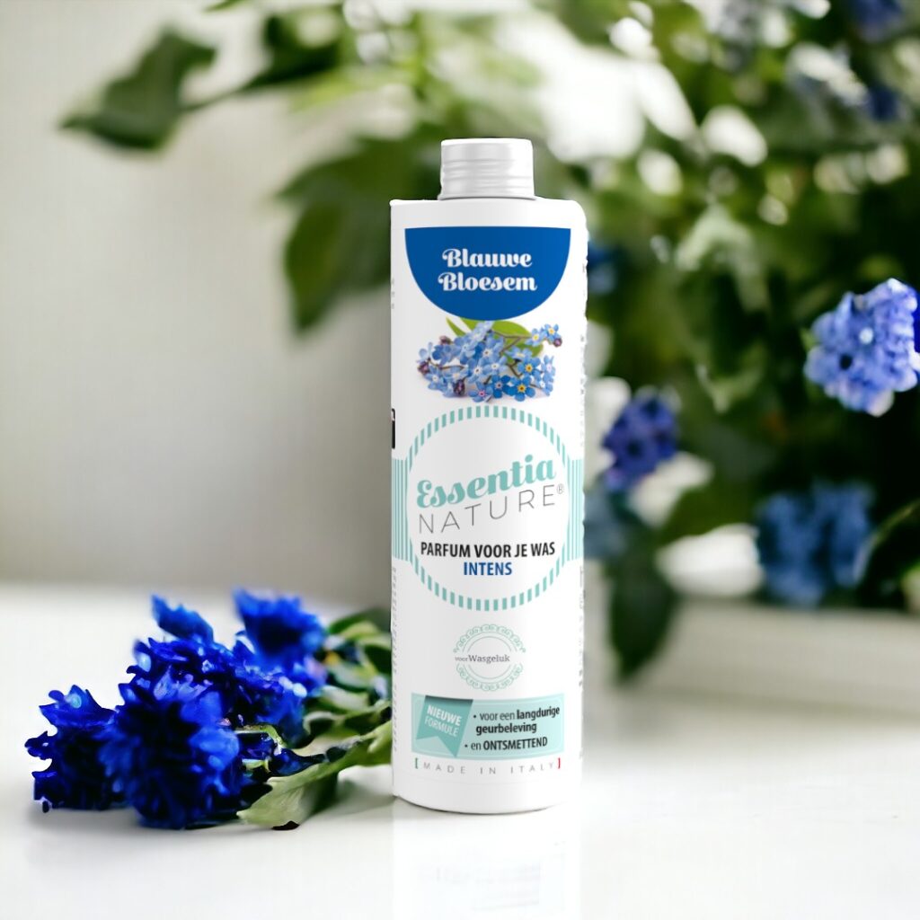 Essentia Wasparfum Blauwe Bloesem toont verse blauwe bloemen met zacht vervaagde groene bladeren op de achtergrond.