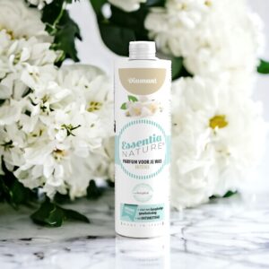 Essentia Wasparfum Diamant, in een elegante fles met pastelkleurige en bloemendetails, straalt frisheid uit te midden van witte bloemen op marmer.