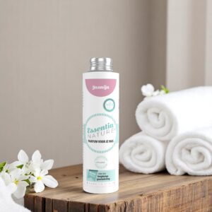 De Essentia Wasparfum Jasmijn 250 ml staat op een houten oppervlak naast opgevouwen witte handdoeken en sierlijke witte bloemen.