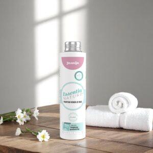 Essentia Wasparfum Jasmijn 250 ml staat op een houten oppervlak naast een opgerolde witte handdoek en bloemen in zacht zonlicht.