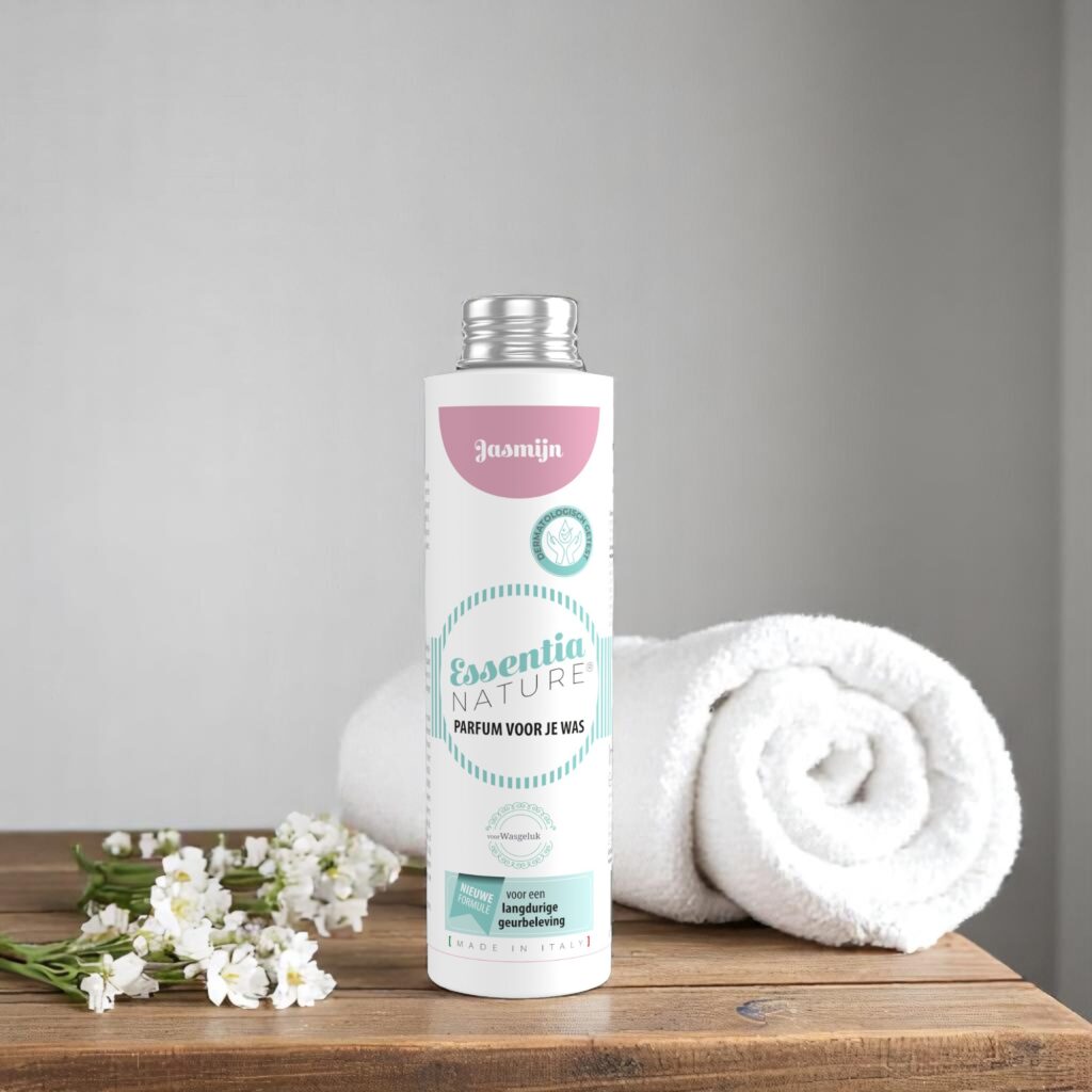 Op een houten oppervlak staat de Essentia Wasparfum Jasmijn-fles van 250 ml naast een opgerolde witte handdoek en witte bloemen.