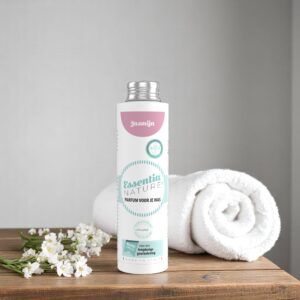 Op een houten oppervlak staat de Essentia Wasparfum Jasmijn-fles van 250 ml naast een opgerolde witte handdoek en witte bloemen.