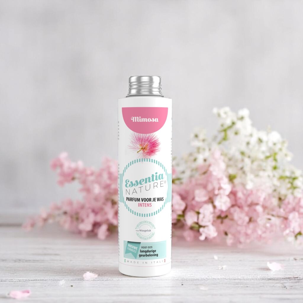 De Essentia Wasparfum Mimosa 250 ml, met pastelkleuren en mimosa-bloemen, steekt af tegen de achtergrond van zachtroze en witte bloemen.