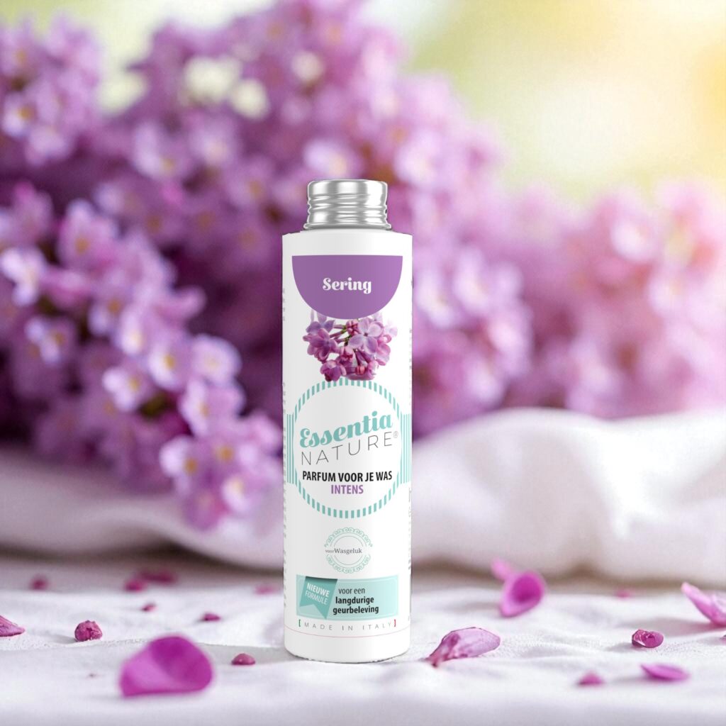 Essentia Wasparfum Sering 250 ml wordt omringd door lila bloemen en bloemblaadjes, met op de achtergrond vervaagde lila bloemen en zacht zonlicht.