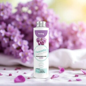 Essentia Wasparfum Sering 250 ml wordt omringd door lila bloemen en bloemblaadjes, met op de achtergrond vervaagde lila bloemen en zacht zonlicht.