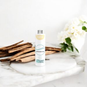 Essentia Wasparfum Vanille en Cashmere staat op een marmeren oppervlak tussen kaneelstokjes en witte bloemen en zorgt zo voor een elegante sfeer.