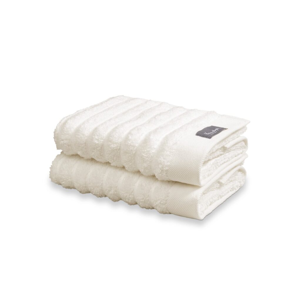 Twee Vandyck Home Wave-handdoeken in de kleur Cream Tan met geribbelde structuur liggen netjes opgestapeld, waarvan één met een grijs label.