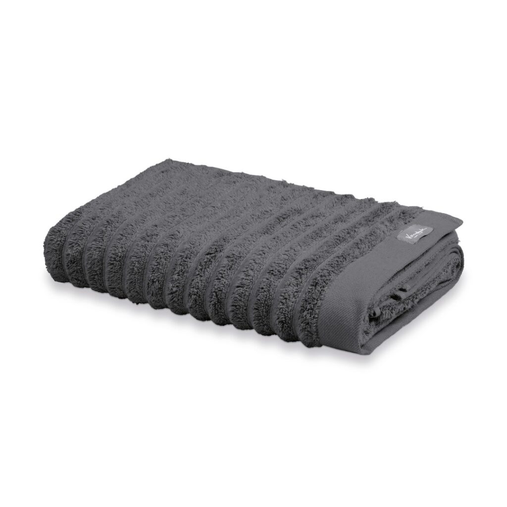 De Vandyck Home Wave-handdoek in donkergrijs heeft een geribbelde structuur en een klein stoffen label, en is netjes opgevouwen.