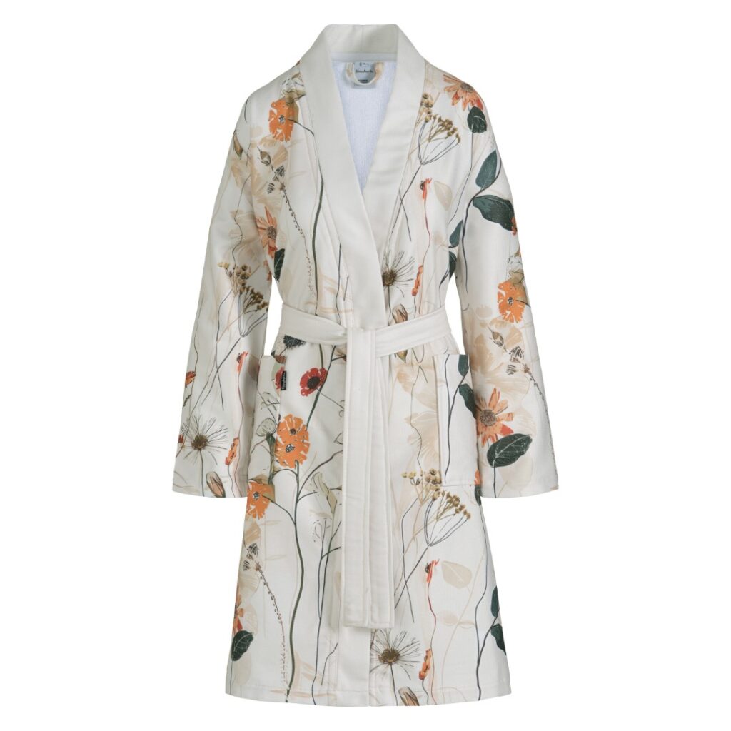 De Vandyck Nova-badjas in de kleur Cream Tan is een witte badjas met een kleurrijk bloemenpatroon in oranje, geel en groen.