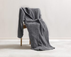 De Clarysse-badjas Billie Grafiet XXL, een zachte donkergrijze badjas met ceintuur, hangt over een houten stoel op een licht tapijt.