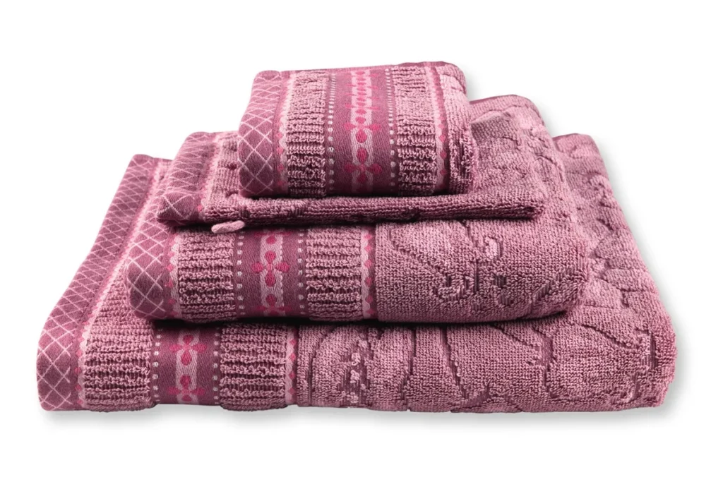 Het Pip Studio Jasmin Jacquard-badlaken in lichtroze heeft een reliëfpatroon en sierlijke randen, en is stijlvol opgevouwen neergelegd.