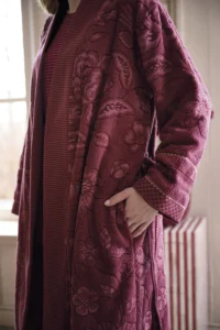 Een persoon poseert in de Pip Studio Jasmin Jacquard-badjas in donkerroze, maat XL, met een lang model, bloemmotief en een zak.