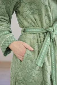 Een persoon draagt de Pip Studio Jasmin Jacquard-badjas Green S met een groen bloemenpatroon, een bijpassende ceintuur en sierlijke manchetten.
